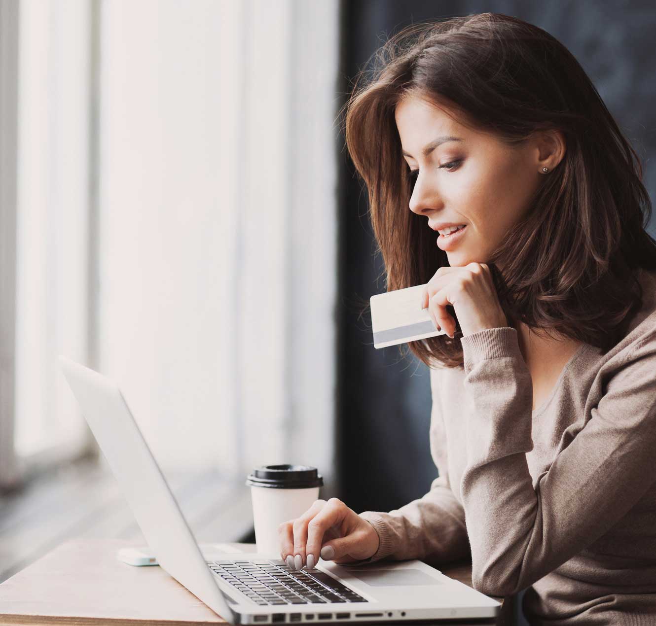 Young woman Holding Credit Card and Using her Laptop
